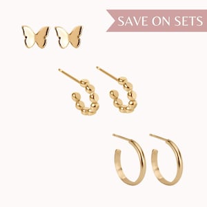 May include: Set of three gold earrings featuring a pair of butterfly stud earrings, a pair of small hoop earrings with a beaded design, and a pair of larger hoop earrings.  SAVE ON SETS