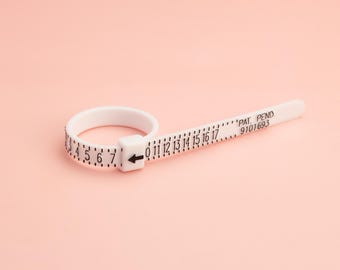 May include: White plastic ring sizer with black markings for measuring ring sizes from 0 to 17. The sizer has the text "PAT. PENDO. 9101693" printed on it.