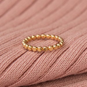 May include: A gold ring with a beaded design. The ring is made of small, round beads that are evenly spaced.