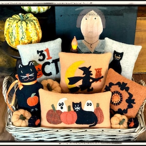 May include: A wicker basket filled with Halloween-themed felt cushions and a black cat plush toy. The cushions feature designs of a witch flying on a broomstick, a black cat, pumpkins, and the text "31 OCT".