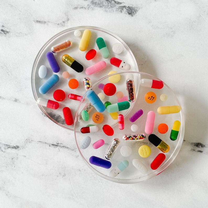 Crystal clear epoxy resin coasters with bright, colorful pills completely embedded.