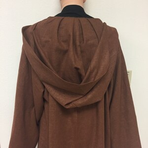 May include: A brown hooded robe with a long, flowing design. The robe is made of a soft, textured fabric.