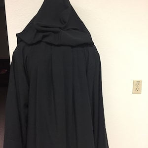 May include: A black hooded robe with a long, flowing design. The robe is made of a soft, smooth fabric.