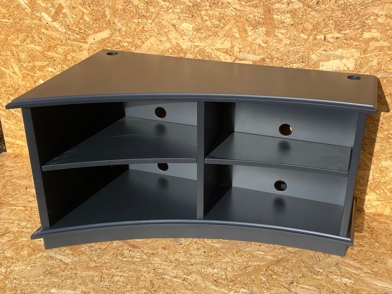 Puede incluir: Soporte de TV de esquina curvo negro con tres estantes y m&uacute;ltiples orificios para la gesti&oacute;n de cables.