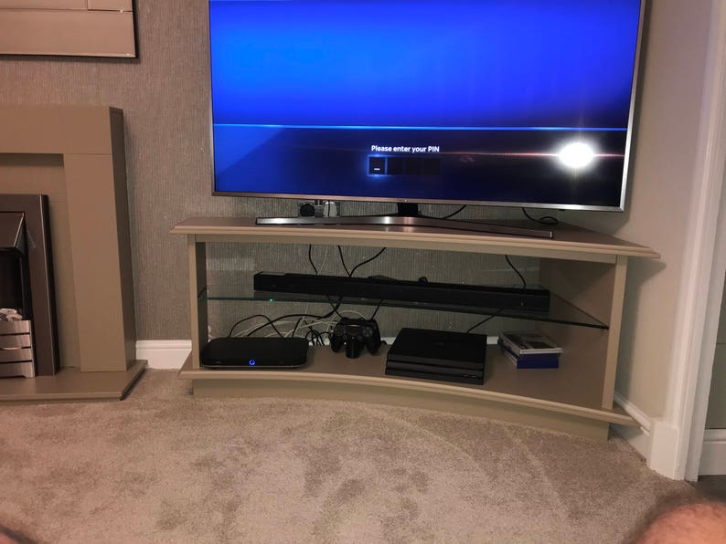 Puede incluir: Un centro de entretenimiento curvo con un televisor de pantalla plana, una barra de sonido y una consola de juegos. La pantalla del televisor muestra el mensaje "Por favor, ingrese su PIN".