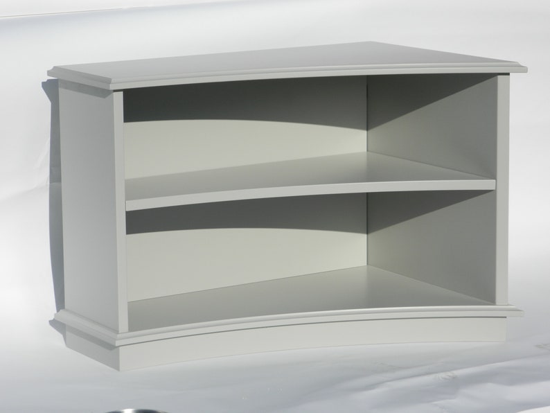Puede incluir: Una estanter&iacute;a de madera gris curvada con dos estantes. Los estantes est&aacute;n curvados para coincidir con la forma de la estanter&iacute;a.