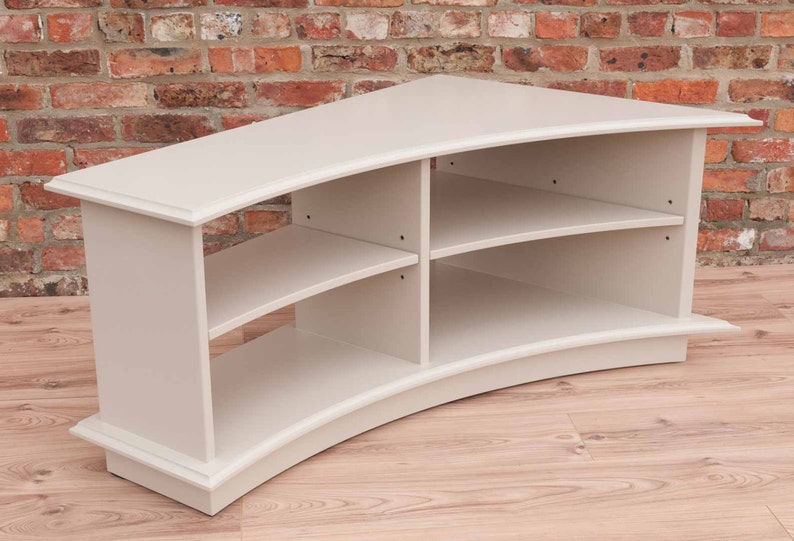 Puede incluir: Un centro de entretenimiento de madera blanca curvado con tres estantes. Los estantes est&aacute;n curvados para que coincidan con la forma de la unidad.