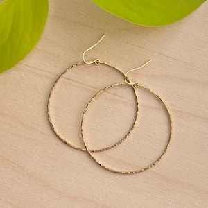 May include: A pair of gold hoop earrings with a textured finish. The earrings are simple and elegant.