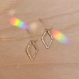 May include: A pair of gold diamond-shaped earrings with a hammered texture.