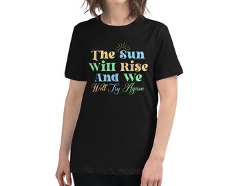 May include: Black t-shirt with a colorful graphic that reads "The sun will rise and we will try again".
