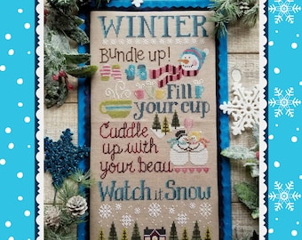 Puede incluir: Un diseño de punto de cruz con la palabra "WINTER" en la parte superior. El diseño incluye un muñeco de nieve, mitones, copos de nieve y las frases "Bundle up!", "Fill your cup", "Cuddle up with your beau" y "Watch it Snow". El diseño está enmarcado con un borde azul y decoraciones invernales.