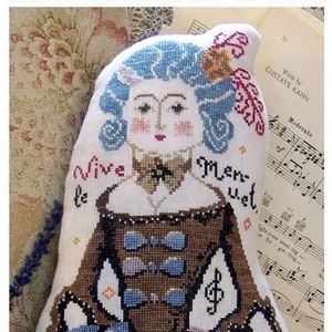 Peut inclure: Un coussin décoratif de la collection "People Pillows", avec un motif au point de croix d'une femme en costume d'époque. Le coussin a des cheveux bleus, une robe marron et le texte "Vive le Menuet".