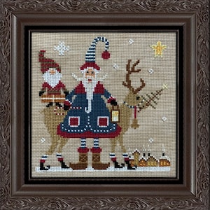 Puede incluir: Obra de arte de punto de cruz en un marco de madera marrón. La imagen representa a Papá Noel montado en un reno, con un pequeño elfo que lleva una bandeja. La escena incluye un pueblo, copos de nieve y una estrella, todo con temática navideña.
