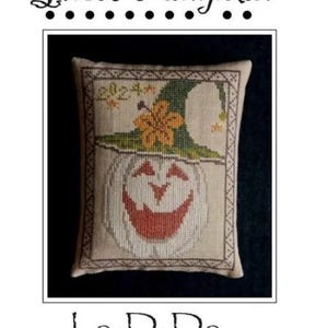 May include: A cross-stitch design featuring a smiling ghost pumpkin wearing a green witch hat with a yellow flower. The design is framed with a decorative border and includes the text "Ghost Pumpkin" and "La-D-Da designs for counted thread".