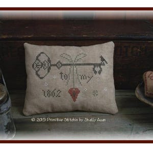 May include: A beige pillow with a cross-stitch design of a key with a heart and the text "to my 1862".