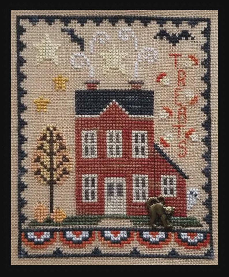 May include: Cross-stitch sampler featuring a red house with a black roof, surrounded by Halloween-themed elements. The word "TREATS" is stitched vertically. Includes stars, a tree, pumpkins, a ghost, and a decorative border.