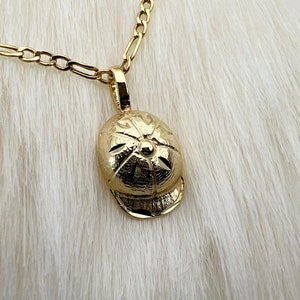 May include: A gold chain necklace with a gold pendant shaped like a baseball cap.