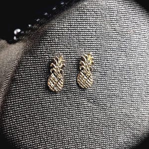 以下が含まれることがあります： 金色のパイナップル形のイヤリングのペア。イヤリングは小さく繊細で、パイナップルが好きな人に最適なギフトになります。