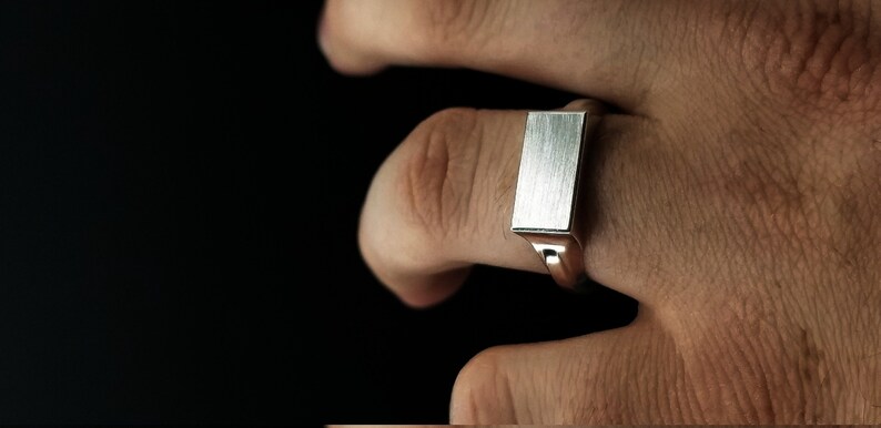 Peut inclure: Une bague signet en argent avec un dessus rectangulaire en m&eacute;tal bross&eacute;.