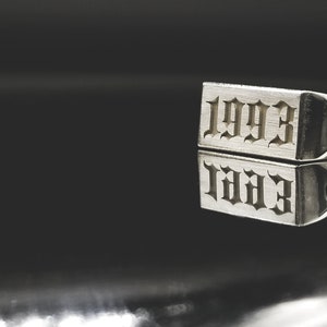 Peut inclure: Une bague en argent avec l'ann&eacute;e 1993 grav&eacute;e en police gothique.
