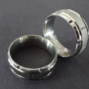 May include: Two silver rings with a textured design. The rings are stacked on top of each other.
