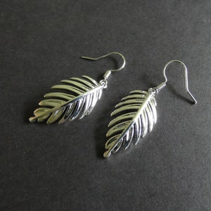 May include: A pair of silver earrings with a leaf design. The leaves are detailed and have a textured surface.