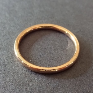 May include: A simple gold band ring.