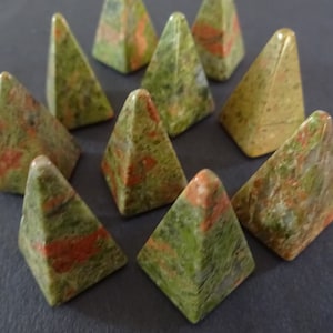 May include: Nine green, red, and white pyramid-shaped stones. The stones are polished and have a mottled appearance.