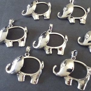 May include: Silver-toned metal elephant pendant charms with an open oval space for adding a photo or other embellishment. The charms have a loop at the top for attaching to a necklace or bracelet.