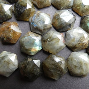 May include: A collection of 17 faceted labradorite gemstone cabochons in various shades of gray, green, and brown. The stones have a unique iridescent sheen.