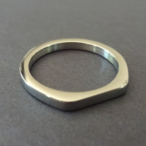 May include: A silver ring with a flat, squared-off band.