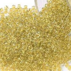 May include: A large quantity of small, clear, yellow glass beads.