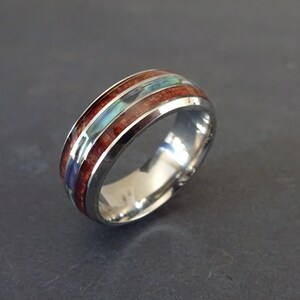 May include: A silver ring with a wooden band inlaid with blue and green abalone shell.