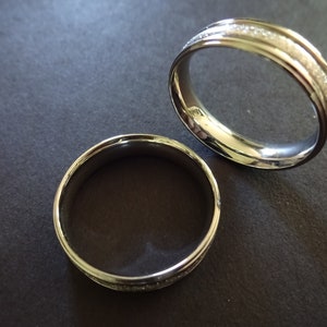 May include: Two silver wedding bands, one with a textured finish and the other with a smooth finish.