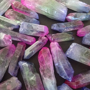 May include: A collection of iridescent crystal points in shades of pink, purple, and blue. The points are arranged on a dark surface.