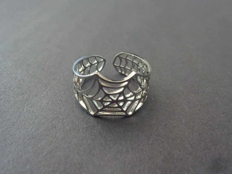 Op de afbeelding: Een verstelbare zilveren ring met een spinnenwebontwerp.