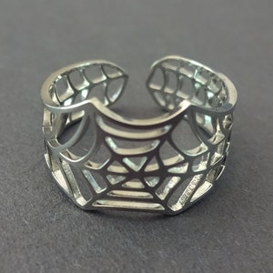 Op de afbeelding: Een verstelbare zilveren ring met een spinnenwebontwerp.