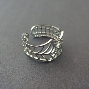 Op de afbeelding: Een verstelbare zilveren ring met een spinnenwebontwerp.