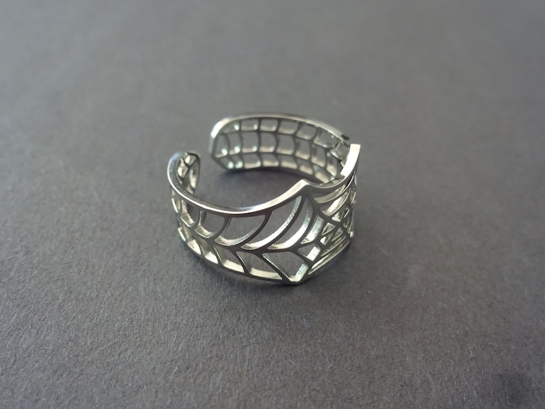 Op de afbeelding: Een verstelbare zilveren ring met een spinnenwebontwerp.
