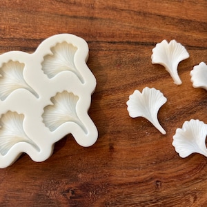 May include: White silicone mould with four ginkgo leaf shapes. Five white ginkgo leaf shapes are shown next to the mould.