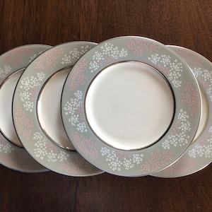 May include: Set of four white ceramic dinner plates with a gray and pink floral pattern.