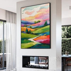 May include: A framed abstract landscape painting with vibrant colors. The artwork features rolling hills in shades of green, orange, and purple, under a sky of pink, yellow, and blue. A winding path leads through the landscape.
