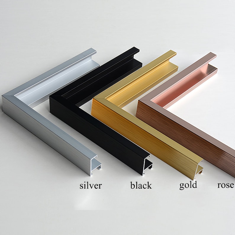 May include: A selection of metal picture frame corners in silver, black, gold, and rose gold. The colors are labeled below each frame. The frames are designed to hold artwork or photos and are displayed on a white surface.