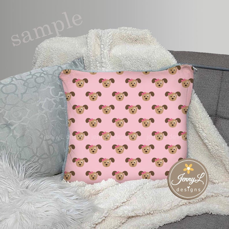 Peut inclure: Un coussin rose avec un motif r&eacute;p&eacute;t&eacute; de visages de chiens bruns avec des n&oelig;uds roses. Le coussin est sur une couverture blanche moelleuse et un canap&eacute; gris. Le texte "Jenny L designs" est sur le coussin.
