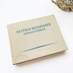 May include: A beige book with the title "DEUTSCH-RUSSISCHER SPRACHFÜHRER" printed in blue.