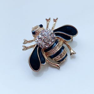 ガラスのラインストーンと黒のエナメルを使用したヴィンテージの金属製ブローチペンダント。空飛ぶ蜂の形をしています。