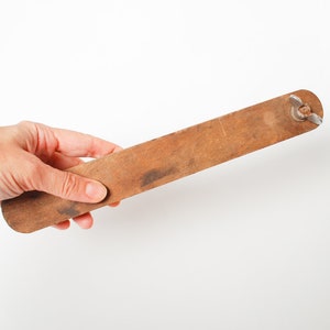 Op de afbeelding: Een houten liniaal met een metalen eindkap. De liniaal is bruin en heeft een versleten oppervlak.