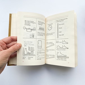 May include: A book with illustrations and text about measuring temperature, time, length, and volume. The illustrations include a thermometer, a clock, a ruler, a measuring cup, a pot of boiling water, a fridge, and a foot.