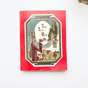 May include: A red book cover with a black and white illustration of two men in top hats. The text "Topsy Turvy World" is printed on the cover.
