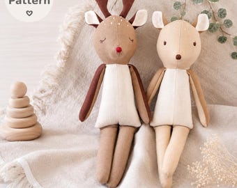 May include: Two plush deer dolls with fabric bodies. One doll has dark brown antlers and a red nose, while the other has light tan ears and a brown nose. Beside them is a stack of five smooth wooden rings. Text reads: PDF Pattern.
